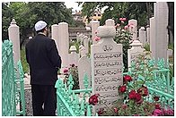 un fedele in preghiera al cimitero
